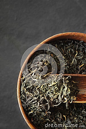 Tea leaves on the wooden bowl on the dark stone background vertical Stock Photo