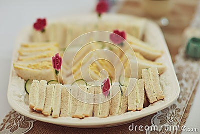 Tea parties wont be the same without a sandwich snack. triangular sandwiches on a table at a tea party inside. Stock Photo