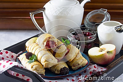 Tea and sliced home apple minischtrudel with fresh apples, cherries, blackberries and sugar powder on an antique wooden background Stock Photo