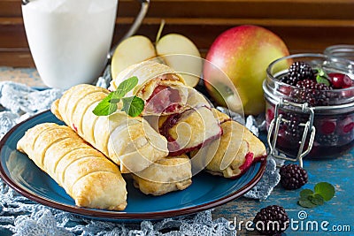 Tea and sliced home apple minischtrudel with fresh apples, cherries, blackberries and sugar powder on an antique wooden background Stock Photo