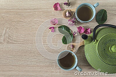 Tea time concept. Green iron tea pot, two cup of tea, rose buds and petals, leaves Stock Photo