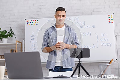 Teach students online from home at COVID-19 epidemic and answer questions from followers. Attractive guy looks at camera Stock Photo