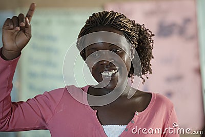 Teacher in Africa, smiling young woman shows students how to put up hands, Primary School, Uganda Editorial Stock Photo