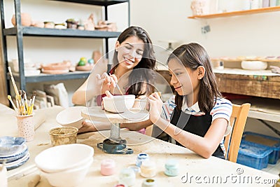 Teacher Assisting Girl To Unleash Her Creativity Of Pottery Pain Stock Photo