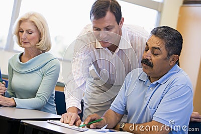 Teacher assisting mature student in class Stock Photo