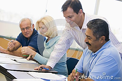 Teacher assisting mature student in class Stock Photo