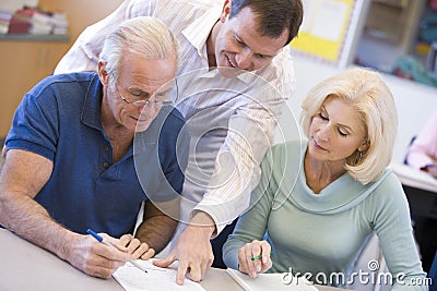 Teacher assisting mature students in class Stock Photo