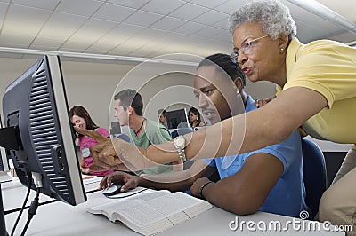 Teacher Assisting Student In Computer Class Stock Photo