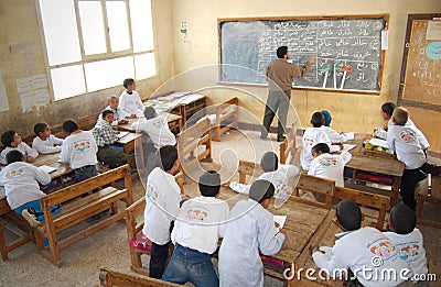 Teacher in classroom writing on blackboard Editorial Stock Photo