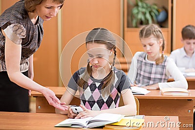 Teacher confiscating schoolkid& x27;s mobile phone at lesson Stock Photo