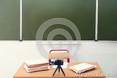 Teacher desk, blackboard and a video camera filming an online lesson, no people. Empty school table, nobody Stock Photo