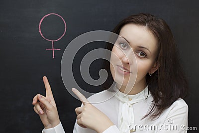 Teacher girl at the chalkboard shows the gender symbol of a woman. Sex ed Stock Photo