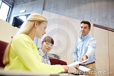 Teacher giving exam tests to students at lecture Stock Photo