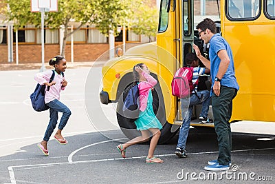 Teacher giving high five to kids while entering in bus Stock Photo