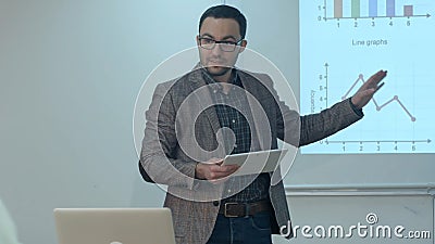 Teacher giving lesson to students using digital tablet in classroom Stock Photo