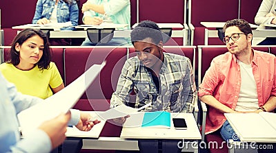 Teacher giving tests to students at lecture Stock Photo