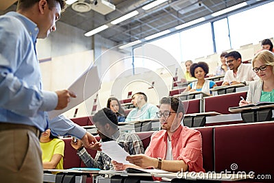 Teacher giving tests to students at lecture Stock Photo