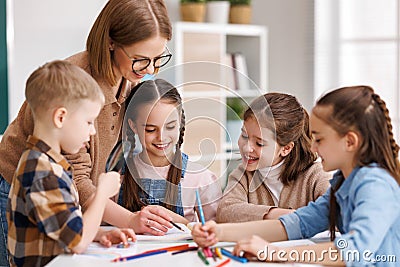 Teacher helping children with schoolwork at school Stock Photo