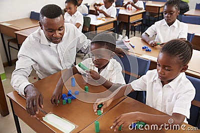 Teacher helping elementary school kids counting with blocks Stock Photo