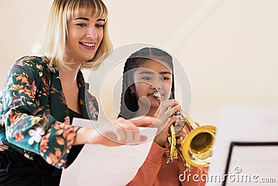 Teacher Helping Female Student To Play Trumpet In Music Lesson Stock Photo