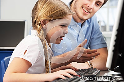 Teacher helping girl using computer in class Stock Photo