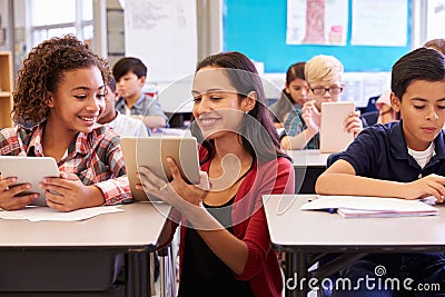 Teacher helping kids with computers in elementary school Stock Photo