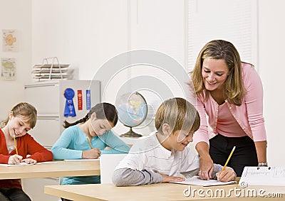 Teacher helping student in classroom Stock Photo