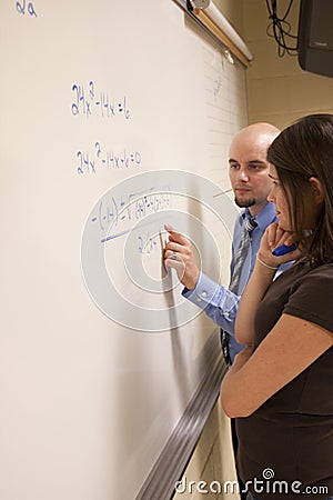Teacher helping student with a math problem on a whiteboard. Stock Photo