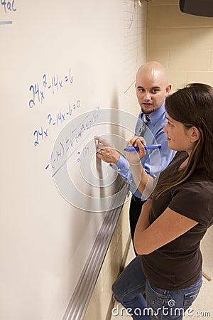 Teacher helping student with a math problem on a whiteboard. Stock Photo