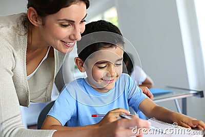 Teacher helping young boy writing Stock Photo