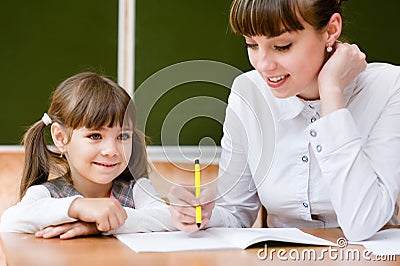 Teacher helping young girl with writing lesson Stock Photo