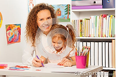 Teacher helps her pupil to write at a copybook Stock Photo