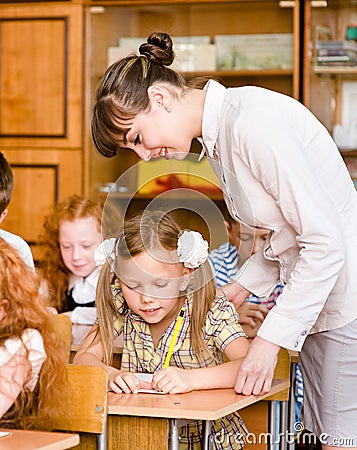 Teacher helps the student with schoolwork in school classroom Stock Photo