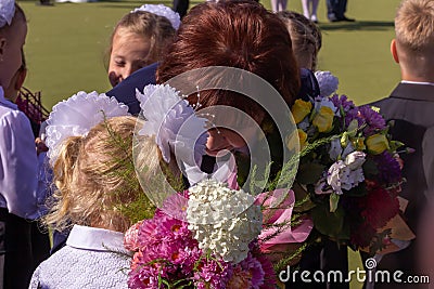 A teacher with holiday bouquet calms down crying first grade girl. First school day of russian children. Editorial Stock Photo