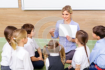 Teacher and kids are sitting in circle together Stock Photo