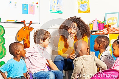 Teacher in kindergarten reading a book to kids Stock Photo