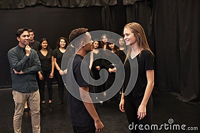 Teacher With Male And Female Drama Students At Performing Arts School In Studio Improvisation Class Stock Photo