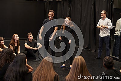 Teacher With Male And Female Drama Students At Performing Arts School In Studio Improvisation Class Stock Photo