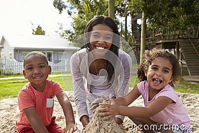 Teacher At Montessori School Playing With Children In Sand Pit Stock Photo