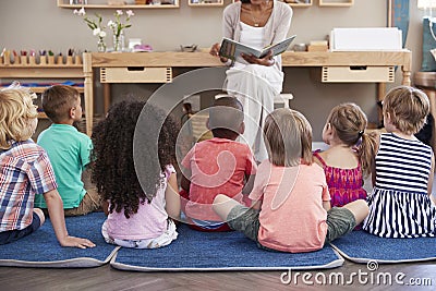 Teacher At Montessori School Reading To Children At Story Time Stock Photo