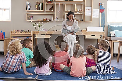 Teacher At Montessori School Reading To Children At Story Time Stock Photo