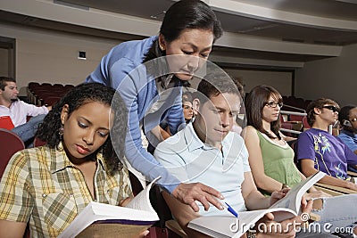 Teacher Pointing In Book While Student Looking Stock Photo