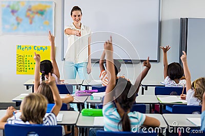 Teacher pointing students with raised hands Stock Photo