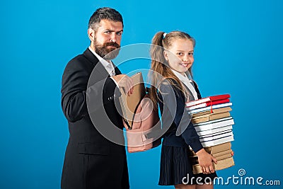 Teacher preparing backpack with school supplies for school child. Little girl with pile of books. Hard to study. Stock Photo