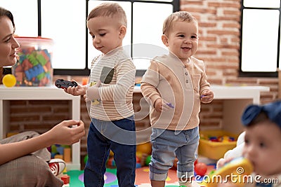 Teacher and preschool students playing with balls and cars standing at kindergarten Stock Photo