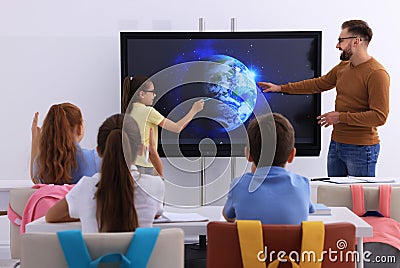 Teacher and pupil using interactive board in classroom during lesson Stock Photo