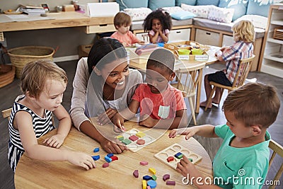 Teacher And Pupils Using Wooden Shapes In Montessori School Stock Photo