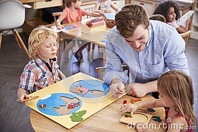 Teacher And Pupils Using Wooden Shapes In Montessori School Stock Photo