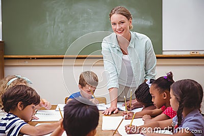 Teacher and pupils working at desk together Stock Photo