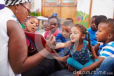 Teacher reading a book with a class of preschool children Stock Photo